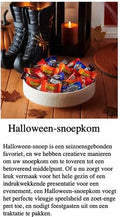 Kom met Halloween-snoepjes op een houten tafel, naast zwarte laarzen en een brandende kaars.