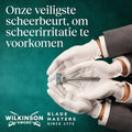 Twee handen met witte handschoenen houden een Wilkinson Sword scheermes vast.